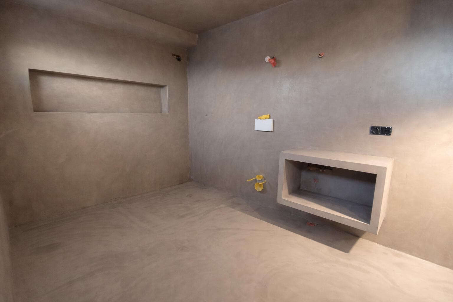 Interior de ODISHOW con suelo y paredes continuos de microcemento y chimenea integrada