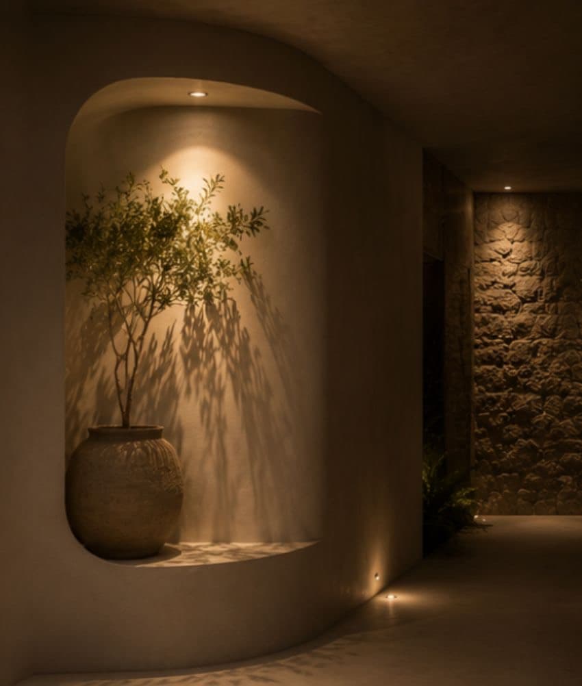 Pasillo curvo de microcemento cálido con iluminación integrada y piedra volcánica